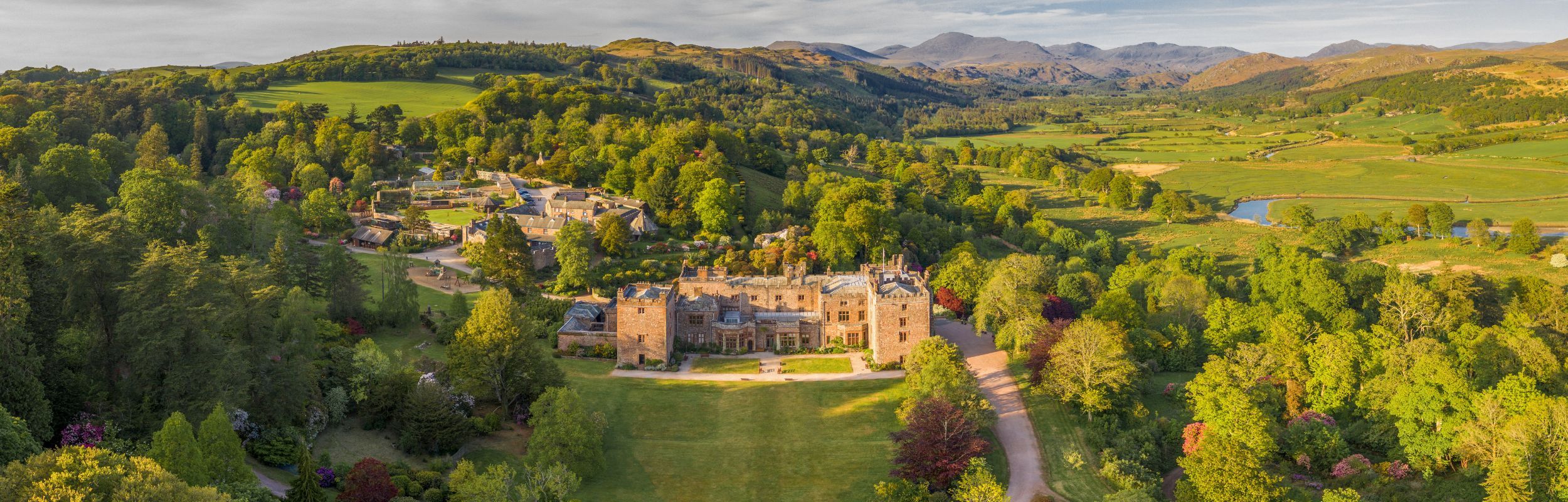 A drone shot of Muncaster Castle and gardens at sunset