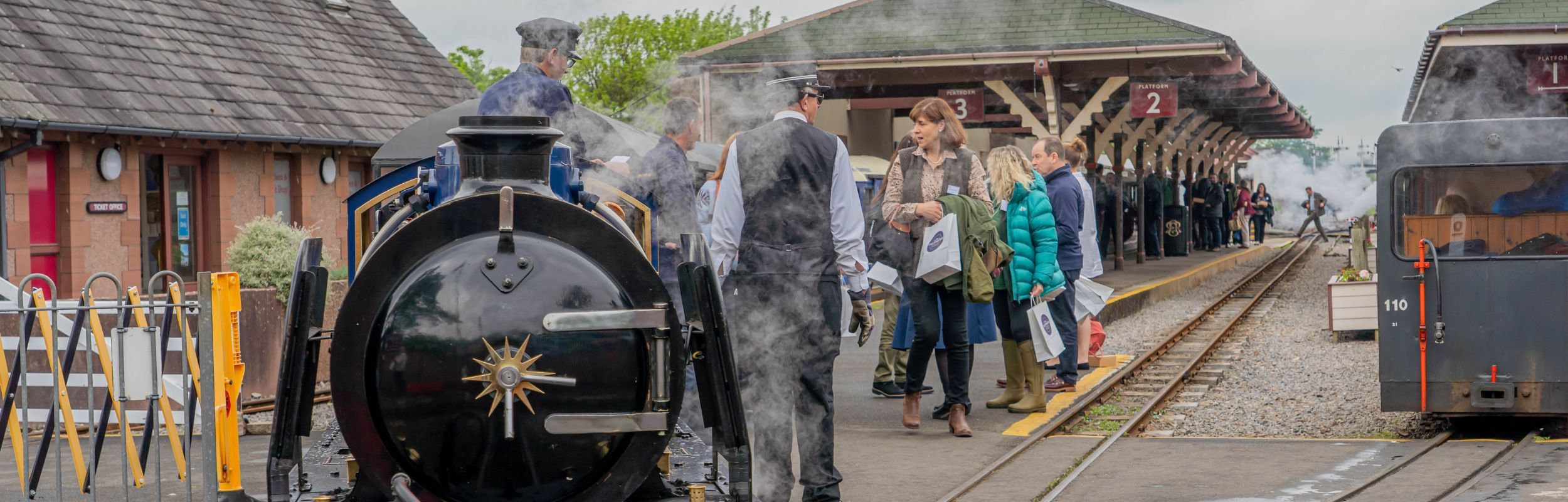 A group disembark the train, led by heritage locomotive Whillan Beck at Ravenglass station
