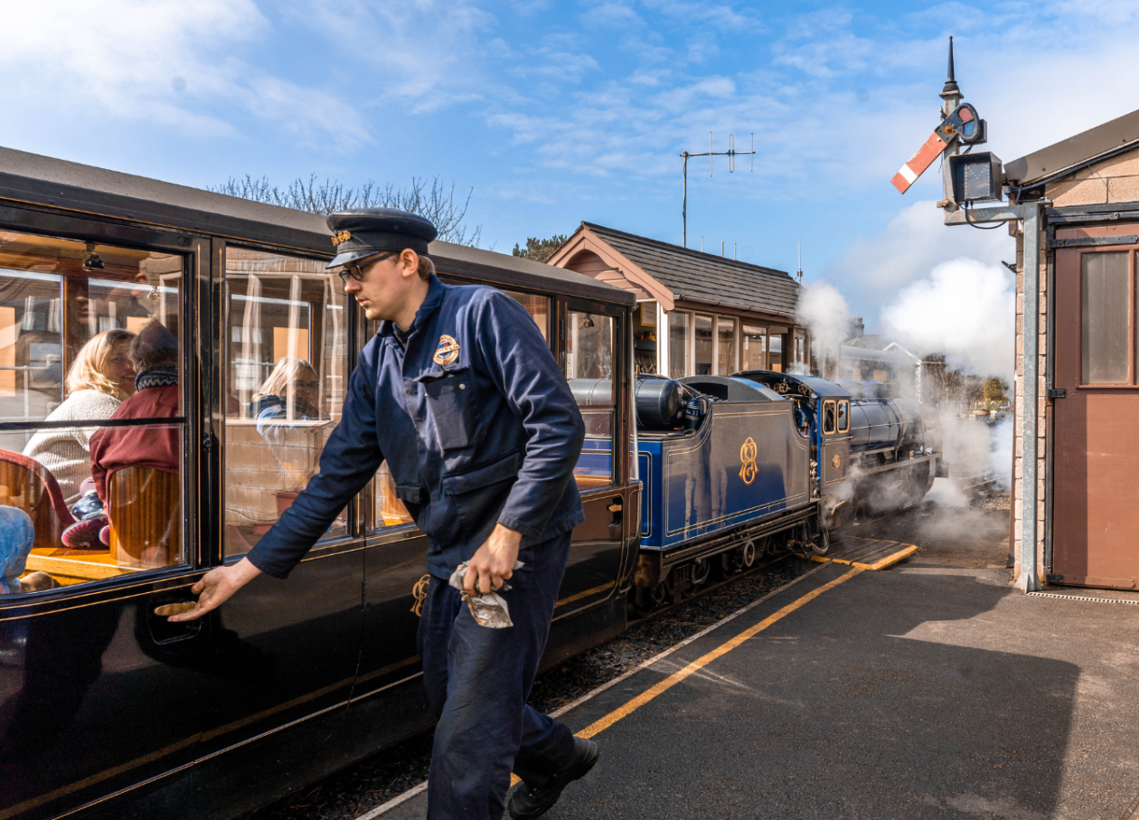 Train driver checking the doors of the 'Joan' Pullman Observation carriage ahead of departing Ravenglass station